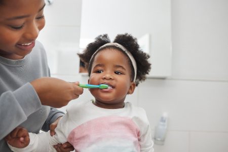 Mom smiling while brushing her daughter's teeth