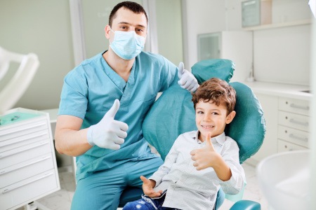 Child and dentist giving thumbs up and smiling